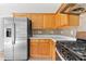 Kitchen showcasing stainless steel refrigerator, gas range, and light wood cabinets with tiled backsplash at 8750 Radford Ln, Suwanee, GA 30024