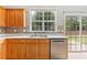 Kitchen featuring a double sink, light wood cabinets, and stainless steel dishwasher with a view of the backyard at 8750 Radford Ln, Suwanee, GA 30024