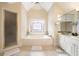 Bright bathroom with a jacuzzi tub under the stained glass window, plus a glass shower door and double sink vanity at 125 Savannah Estates Dr, Atlanta, GA 30350