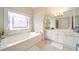 Light and airy bathroom with jacuzzi tub under a stained glass window and white cabinets and drawers at 125 Savannah Estates Dr, Atlanta, GA 30350
