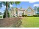 Two-story tan home featuring manicured landscaping, dormer windows and a beautiful entry door at 125 Savannah Estates Dr, Atlanta, GA 30350
