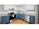 Bright kitchen featuring white and blue cabinets, stainless steel appliances, granite countertops, and hardwood floors at 7750 Roswell Rd # 3D, Atlanta, GA 30350