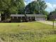 Brick house with an attached garage and driveway is surrounded by mature trees and an unkempt lawn at 1024 Topaz Lane, Villa Rica, GA 30180