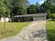Exterior view of a brick home featuring an attached garage and a long driveway, surrounded by mature trees at 1024 Topaz Lane, Villa Rica, GA 30180