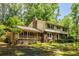 Two-story home with stone accents, a covered porch, and a lush green lawn and mature trees at 5410 Rosser Rd, Stone Mountain, GA 30087