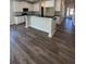 Open concept kitchen with white cabinets, a kitchen island with bar seating, and wood flooring at 3806 Lockaby Way, Lawrenceville, GA 30044