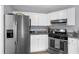 Compact kitchen features stainless steel refrigerator and appliances paired with white cabinets and granite countertops at 1359 Chatley Way, Woodstock, GA 30188