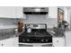 Close-up of kitchen range area featuring granite countertops with modern appliances and storage at 1359 Chatley Way, Woodstock, GA 30188