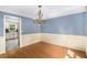 Elegant dining area with chandelier, wainscoting, wood floors, and adjacent access to the kitchen at 106 Waterford Place Pl, Acworth, GA 30101