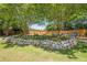 Backyard featuring a rock wall, lush landscaping, and inviting seating area with blue Adirondack chairs at 2304 Mitford Ct, Dacula, GA 30019