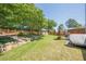 Green backyard with a rock retaining wall, small shed, and patio seating area at 2304 Mitford Ct, Dacula, GA 30019