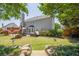 Landscaped backyard featuring a patio area, green lawn, mature trees, and a stone retaining wall at 2304 Mitford Ct, Dacula, GA 30019