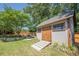 Backyard shed featuring neutral siding, a wood door, and a ramp with lawn and landscaping at 2304 Mitford Ct, Dacula, GA 30019