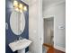 Stylish powder room with pedestal sink, oval mirror, decorative lighting, and wainscoting, adding a touch of elegance at 4677 Prater Se Way, Smyrna, GA 30080