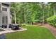 A backyard featuring a stone patio with outdoor seating, a lush lawn, and mature trees, perfect for relaxation and entertainment at 870 River Cliff Ct, Suwanee, GA 30024