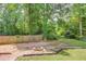 Large, wooded backyard with wooden fence and fire pit surrounded by mature trees offers privacy at 905 Foxfire Dr, Lawrenceville, GA 30044