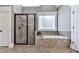 Bathroom featuring a glass-enclosed shower, soaking tub, and neutral tiling at 237 Libby Ln, Canton, GA 30115