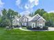 Stunning two-story home featuring a stone chimney, arched windows, and lush green landscaping at 237 Libby Ln, Canton, GA 30115