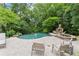 Lush backyard with a gunite pool, spa, stone fireplace and surrounding landscaped greenery at 311 Rolling Rock Se Rd, Marietta, GA 30067