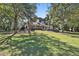 Expansive manicured lawn with mature trees leads up to the beautiful home with a covered patio and dining spaces at 160 Isleworth Way, Fayetteville, GA 30215