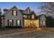 Charming home with stone accents, arched windows, a covered porch, and manicured lawn at dusk at 160 Isleworth Way, Fayetteville, GA 30215