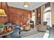 Elegant living room with rich wood paneling, arched windows, plush seating, and a decorative rug at 160 Isleworth Way, Fayetteville, GA 30215