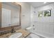 Bathroom with granite countertop, white tile shower, and framed mirror at 2677 Tilson Rd, Decatur, GA 30032