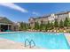 Large community pool with deck chairs and neighboring buildings under a blue sky at 416 Montclair Ct, Woodstock, GA 30188