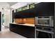 Modern kitchen featuring sleek black cabinetry, stainless steel appliances, and a contrasting wood backsplash at 819 Belgrade Ne Ave, Atlanta, GA 30306