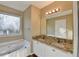 Bathroom featuring a double vanity with granite countertop, soaking tub, and neutral walls at 1400 Scenic Brook Sw Trl, Conyers, GA 30094