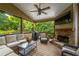 Relaxing covered deck with stone fireplace, comfortable seating, and views of the lush backyard at 200 Glenview Ct, Woodstock, GA 30188