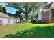 Backyard featuring lush green grass, established trees, and a brick home for a scenic view at 1595 Lake Lucerne Rd Sw, Lilburn, GA 30047
