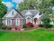 Inviting brick home with a red front door, manicured lawn, and mature trees in a residential area at 1595 Lake Lucerne Rd Sw, Lilburn, GA 30047