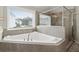 Bright bathroom featuring a soaking tub by a window, and a glass enclosed shower at 6840 Canyon Creek Way, Cumming, GA 30028