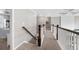 Upstairs hallway with carpet flooring, a wooden handrail, and views of the bedrooms at 6840 Canyon Creek Way, Cumming, GA 30028