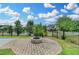 Backyard with stone fire pit, grass area, and black metal fence under a cloudy blue sky at 7470 Oldbury Pl, Cumming, GA 30040
