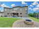 Large backyard featuring a stone fire pit, patio with outdoor seating and grill under a cloudy sky at 7470 Oldbury Pl, Cumming, GA 30040