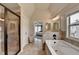 This bathroom features a large tub, tiled shower, double vanity, tile floors, and natural light at 7470 Oldbury Pl, Cumming, GA 30040