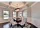 Elegant dining room with coffered ceilings, chandelier, and views to the outdoor patio at 7470 Oldbury Pl, Cumming, GA 30040