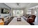 Spacious living room featuring a large leather couch, hardwood floors, and natural light from the windows at 7470 Oldbury Pl, Cumming, GA 30040