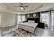 Inviting main bedroom with dark accent wall, tray ceiling, and plush rug at 7470 Oldbury Pl, Cumming, GA 30040