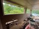 Enclosed porch provides serene views of surrounding green trees and landscape, with riding mower stored inside at 1856 Butler Bridge Rd, Covington, GA 30016
