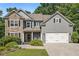 Charming two-story home featuring a stone facade, gray siding, a two-car garage, and manicured landscaping at 27 Rose Brooke Cir, White, GA 30184
