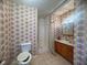 Full bathroom featuring a vanity, a toilet, and a shower-tub combination, all enclosed within floral wallpapered walls at 7125 Chappell Cir, Atlanta, GA 30360