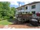 Expansive backyard view of the house, wooden deck with patio set and grill surrounded by lush greenery at 2968 Ovalene Sw Ct, Marietta, GA 30064