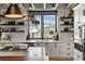 Bright kitchen features white cabinets, open shelving, stainless appliances, and a large window offering scenic outdoor views at 1354 Fernwood Ne Cir, Brookhaven, GA 30319