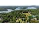 Expansive aerial view showcasing a lakefront property surrounded by lush trees and sparkling blue waters at 5340 Young Deer Dr, Cumming, GA 30041