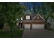 Evening view of charming brick two-story home featuring a two-car garage and landscaped front yard at 5655 Stevehaven Ln, Cumming, GA 30028