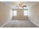Neutral-toned bedroom featuring carpet, ceiling fan, two windows, and a white door at 225 Fireside Way, Fairburn, GA 30213