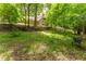 Scenic backyard featuring a green lawn and a charming wrought-iron bench nestled among mature trees at 8470 Lazy Oaks Ct, Atlanta, GA 30350
